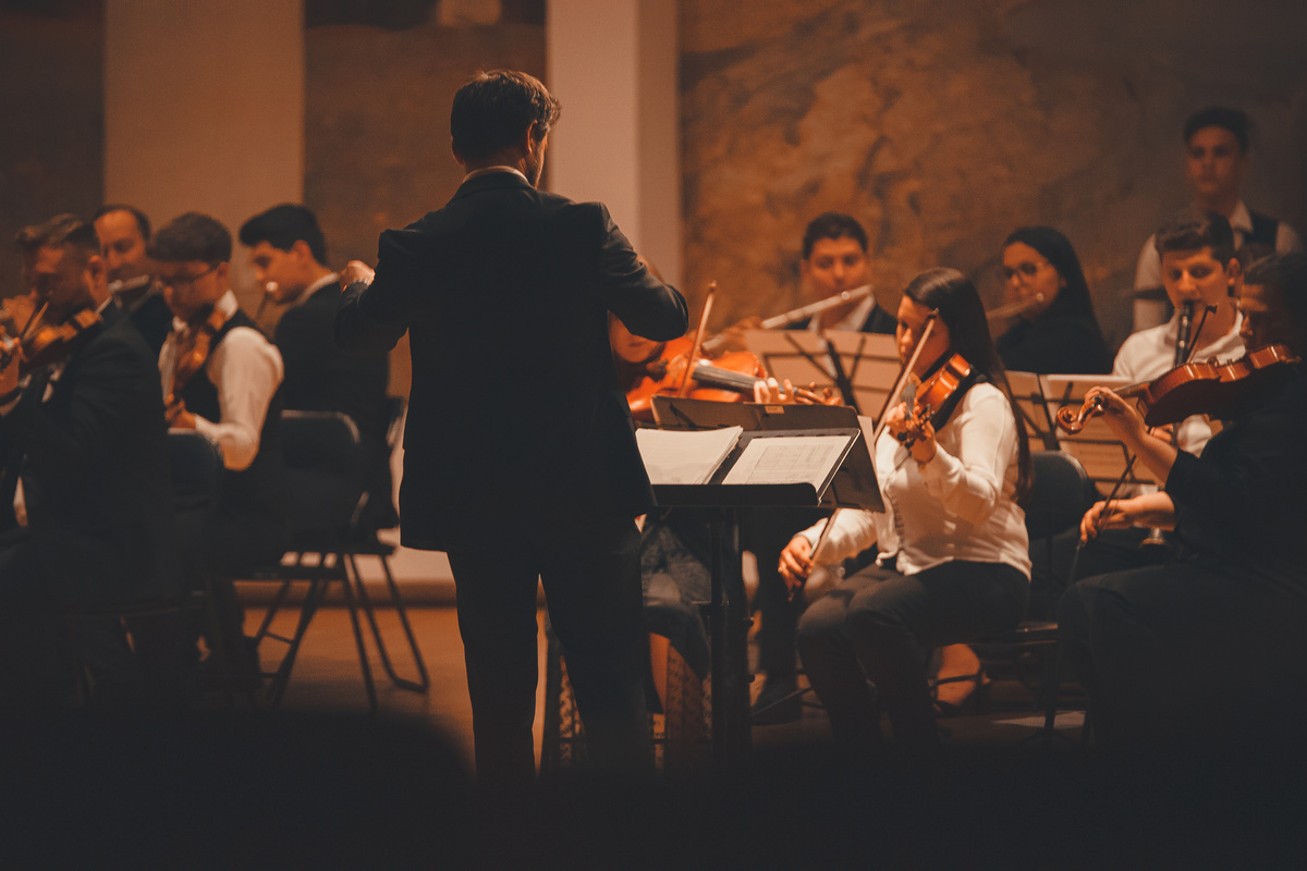 A Person in Black Suit Conducting the Orchestra